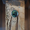 Custom oil-painted dog pendant on a jeweller’s workbench, showing detail and silver craftsmanship.