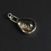 Citrine floral drop intaglio charm at an angle on black, the high dome of the citrine catching the light and the carved stem reading pale against the honey stone
