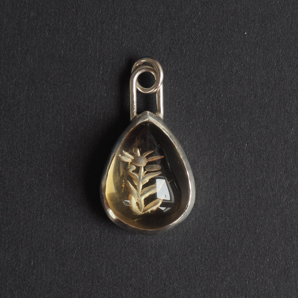 Citrine floral drop intaglio charm - a floral charm, a single flower on a leafy stem reverse-carved into a pear-shaped honey-gold citrine, in a plain silver bezel with a long loop bale