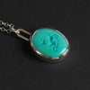Turquoise intaglio dog necklace angled the other way, the chain to the left and the dog's raised head reading against the flat turquoise
