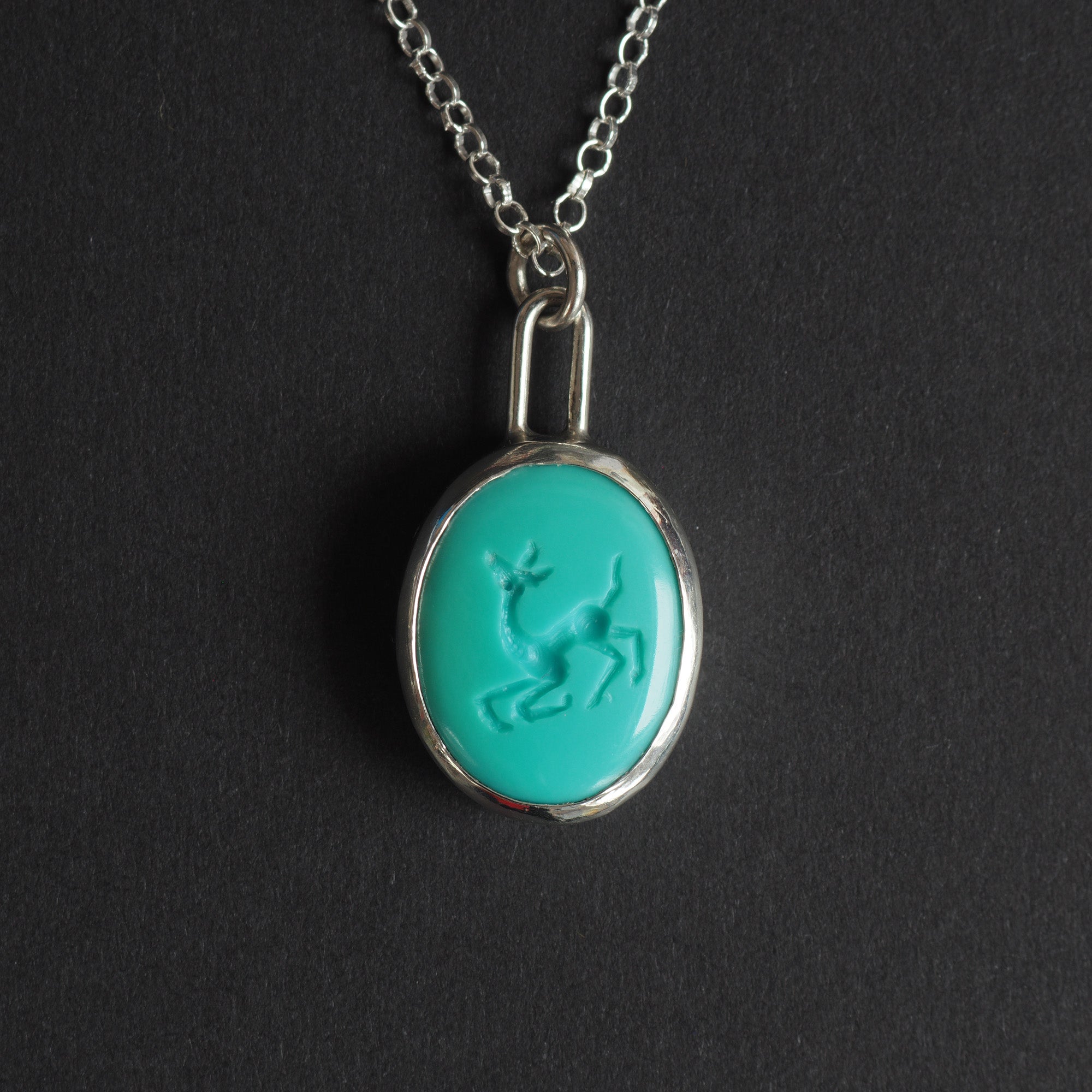 Turquoise intaglio dog necklace - a dog necklace, a long-legged dog mid-caper with its head up and its legs kicking, hand-carved into a bright turquoise oval