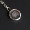 Pink Elephant reverse carved intaglio quartz necklace angled the other way, the silver bezel and long loop bale catching the light, the carving faint from this side