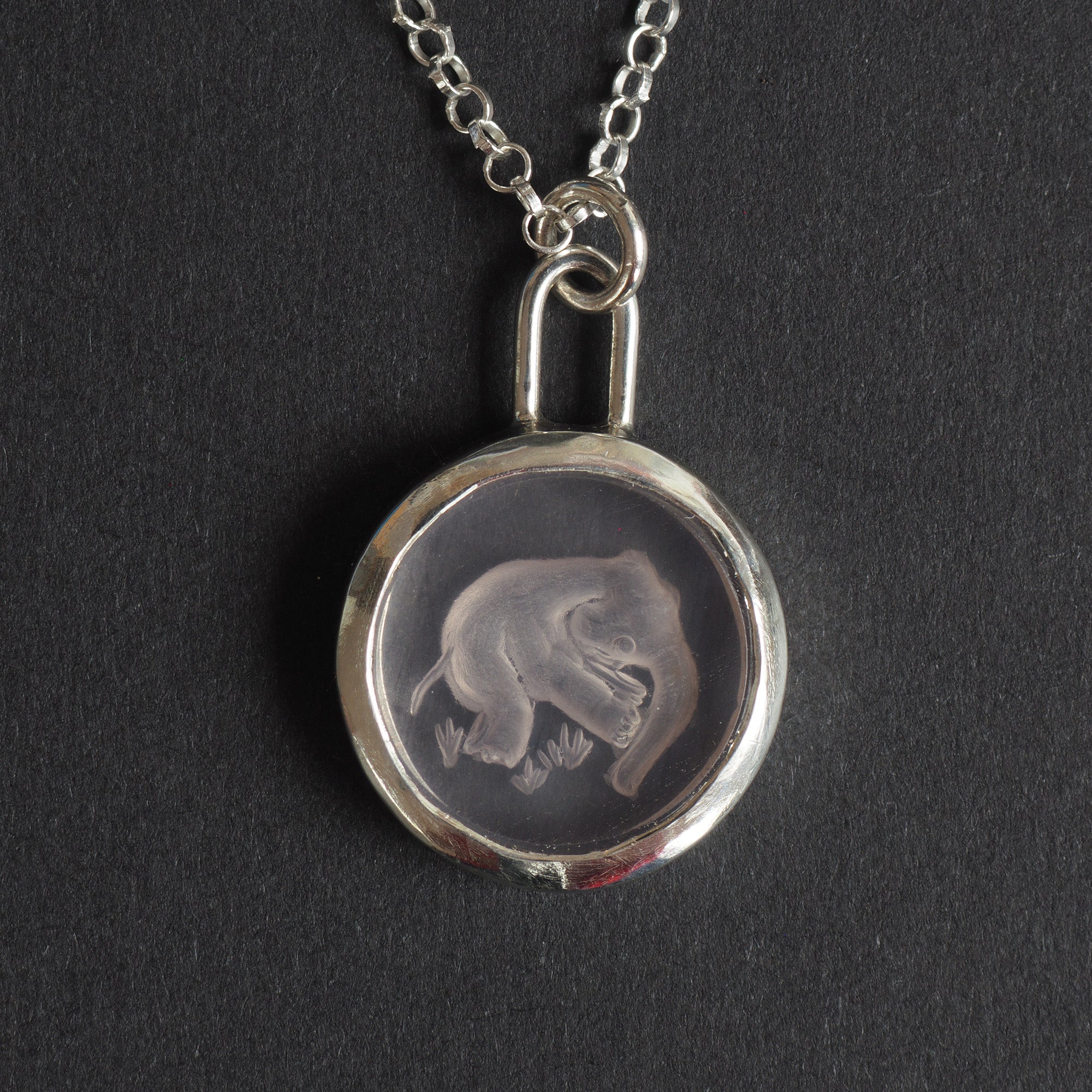 Pink Elephant reverse carved intaglio quartz necklace - an unusual necklace, an elephant caught mid-air, reverse-carved into a disc of the palest pink quartz above tufts of grass