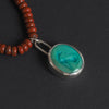 turquoise intaglio cat necklace on red jasper close at the front of its strand, the cat's long ears and upright posture clear in the carving