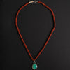 turquoise intaglio cat necklace on red jasper laid out full length on black, brick-red jasper rondelles the whole way and pale agate beads near the clasp