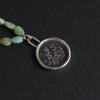 quartz and chrysoprase seaweed intaglio necklace close at the top of its strand, the carved fronds reading white against the dark ground through the crystal