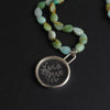 quartz and chrysoprase seaweed intaglio necklace at an angle, the round crystal pendant below its loop bale and the beads curving away above it
