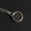 The End Quartz reverse intaglio necklace at an angle on black, the lettering reading in reverse from this side and the bezel's depth along the lower edge