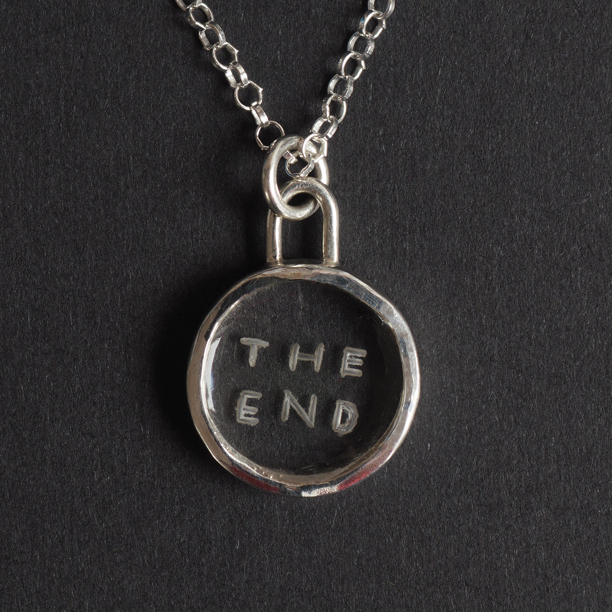 The End Quartz reverse intaglio necklace - an unusual necklace, the words THE END hand-cut in two lines into a small disc of clear rock crystal, in a plain silver bezel