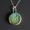 Turquoise Skeletal Torso intaglio necklace hanging front-on against black, the skull's hollow sockets and the ribs and arm bones modelled within the hollow of the stone