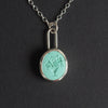 Turquoise Vase of Flowers intaglio necklace hanging front-on, the flower heads and leaves reading clearly in the hollow of the carving